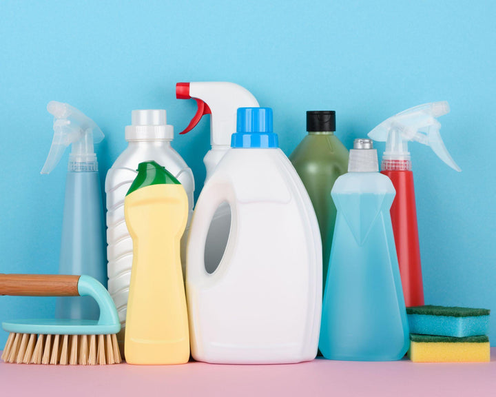 Schoonmaakmiddelen in sprayflacons en flessen op een roze en blauwe achtergrond